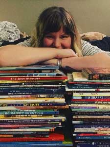 Ashley Speed leaning on a pile of books.