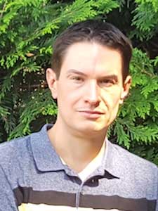 Christopher Dale in gray top in front of greenery.