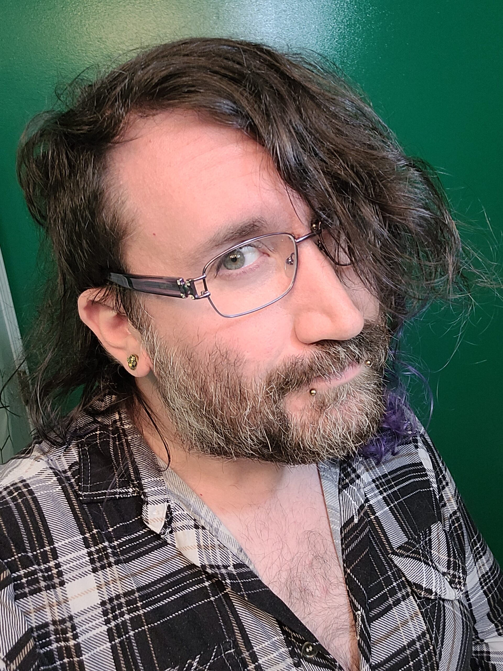 Nonbinary white person in plaid shirt and glasses.