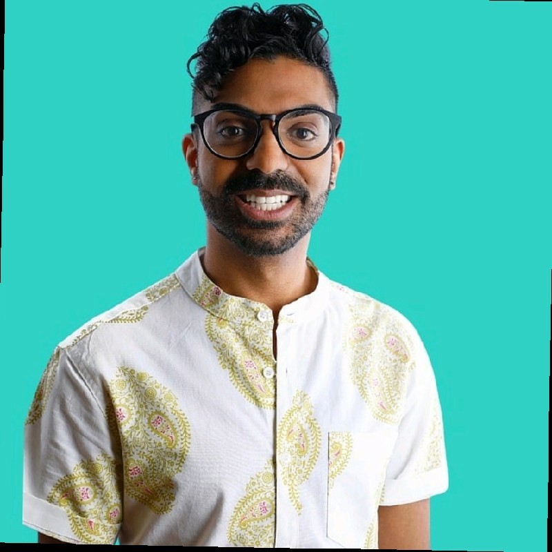 Rahim Thawer smiling in black-framed glasses with teal background